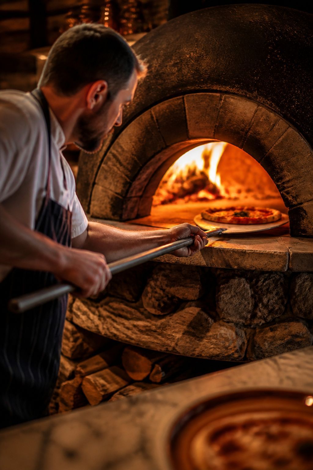 Pizzaïolo enfournant une pizza dans un four à bois